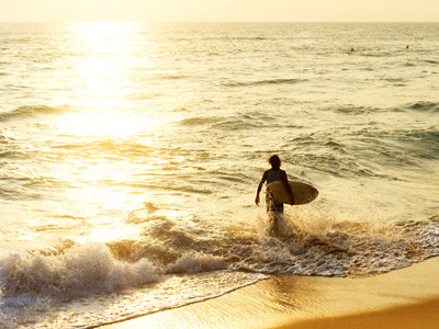 Surfer on the ocean beach at sunset in Hikkaduwa, Sri Lanka